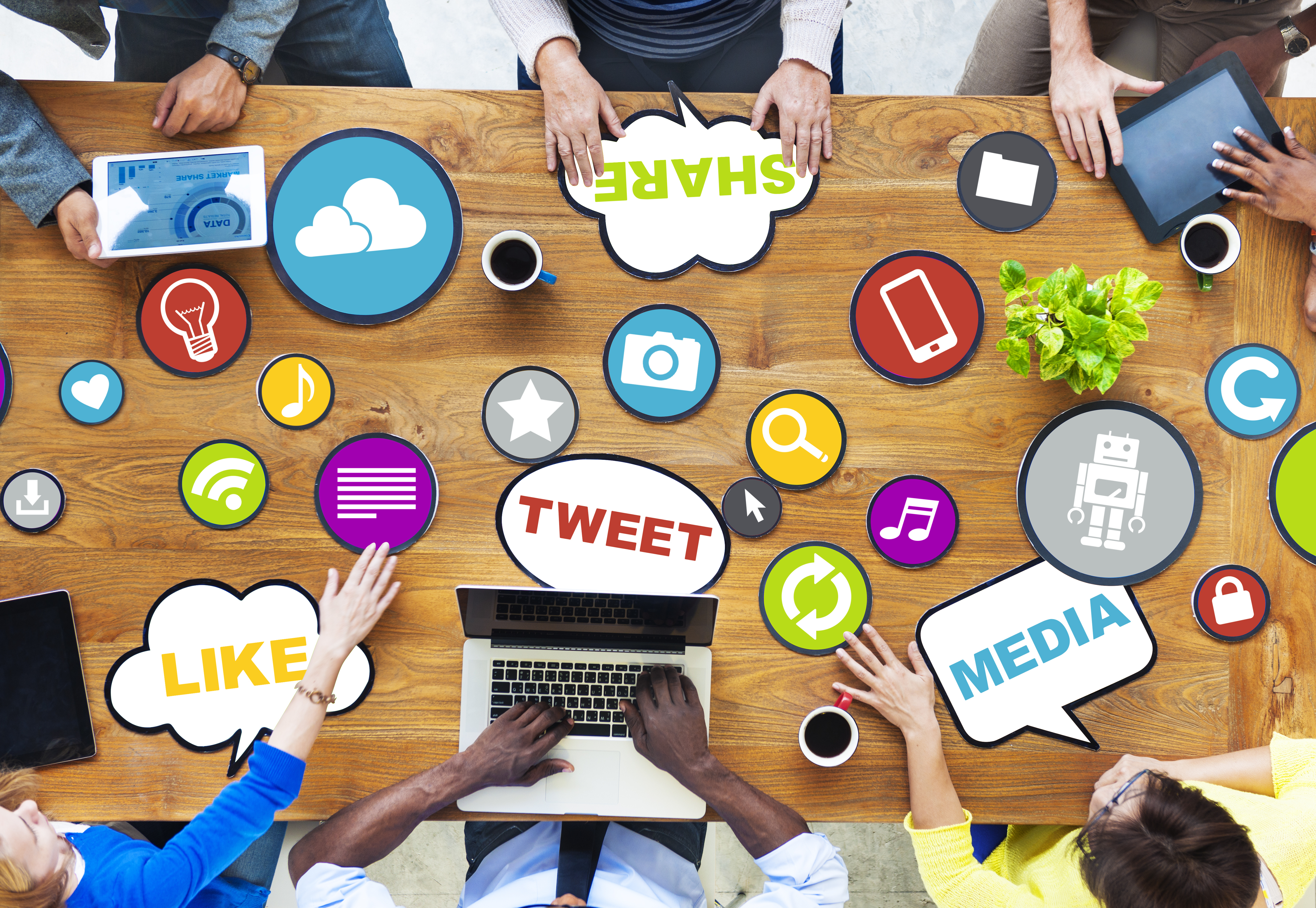 group of people sitting at table with laptops. Digital marketing references are scattered on the table