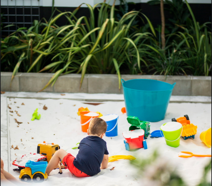 Child playing with toys in outdoor sandpit at The Quarter Acre Hotel